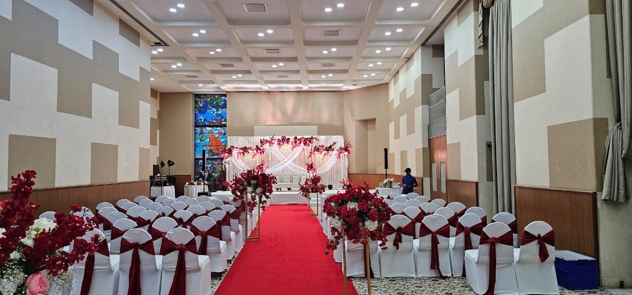 Indoor banquet hall setup with elegant chairs and red carpet walkway